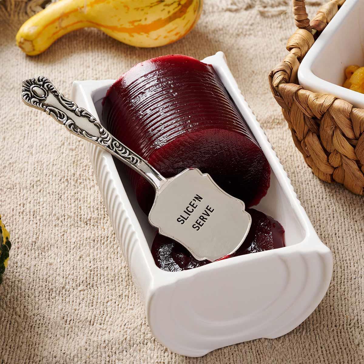 Cranberry Sauce  in a white container with a serving tool on a textured surface