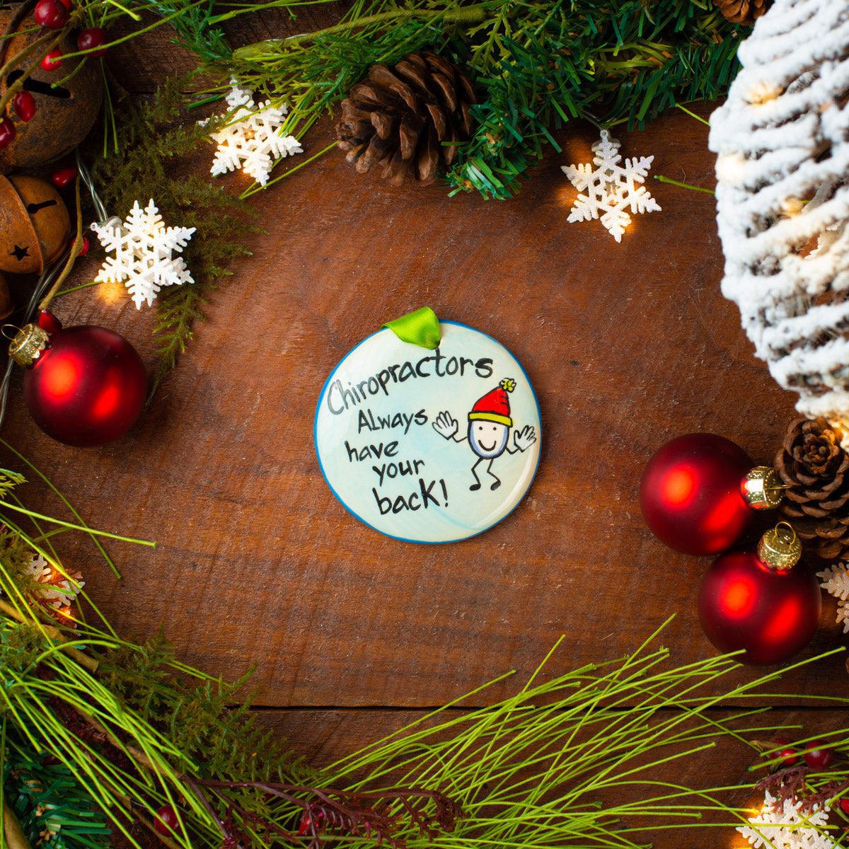 A ceramic ornament with a chiropractor theme, placed on a festive background with Christmas decorations.