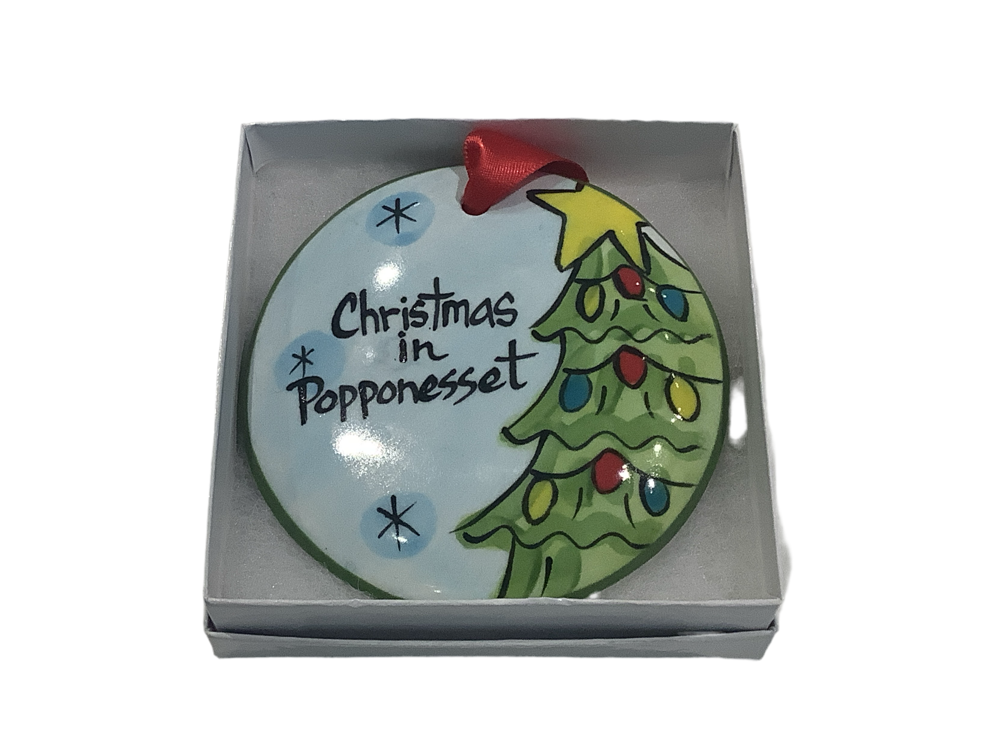A flat, round ceramic ornament with a Christmas tree and the text 'Christmas in Popponesset' painted on it, packaged in a gift box.