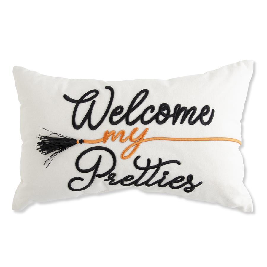 A rectangle white throw pillow featuring embroidered text that reads 'Welcome my Pretties' in black and orange, with a black broom tassel detail, shown against a plain white background.