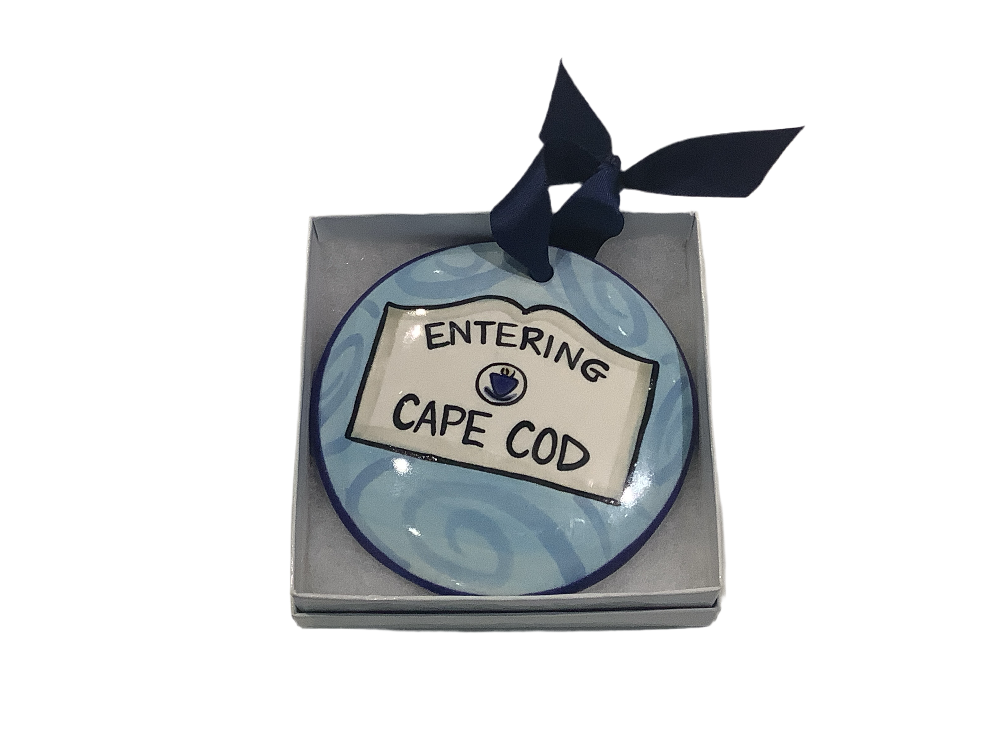 A round ceramic ornament with a blue pattern and text 'ENTERING CAPE COD' on it, tied with a black ribbon at the top.