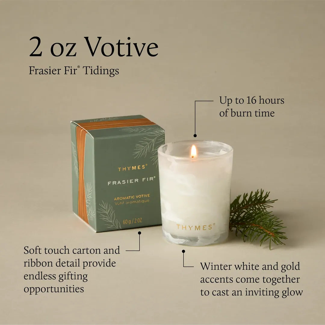 Thymes Frasier Fir Tidings 2 oz boxed votive candle in a swirling winter-white glass vessel with gold accents, displayed beside its green holiday gift box.