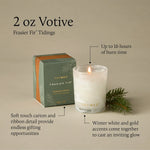 Thymes Frasier Fir Tidings 2 oz boxed votive candle in a swirling winter-white glass vessel with gold accents, displayed beside its green holiday gift box.