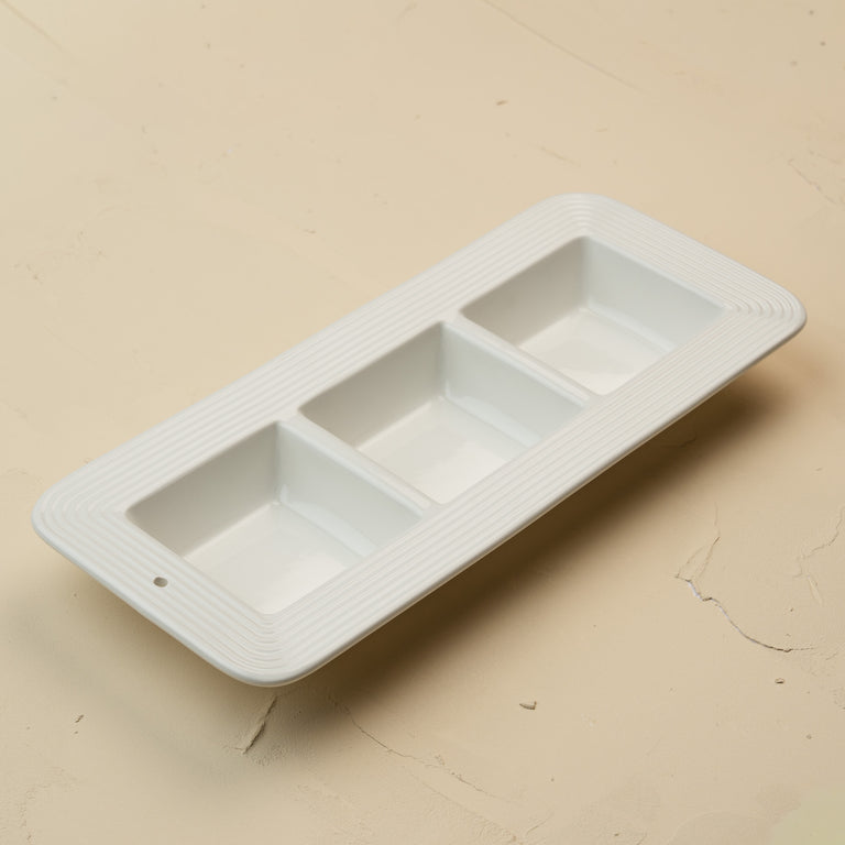 White ceramic tray with three compartments on a beige surface