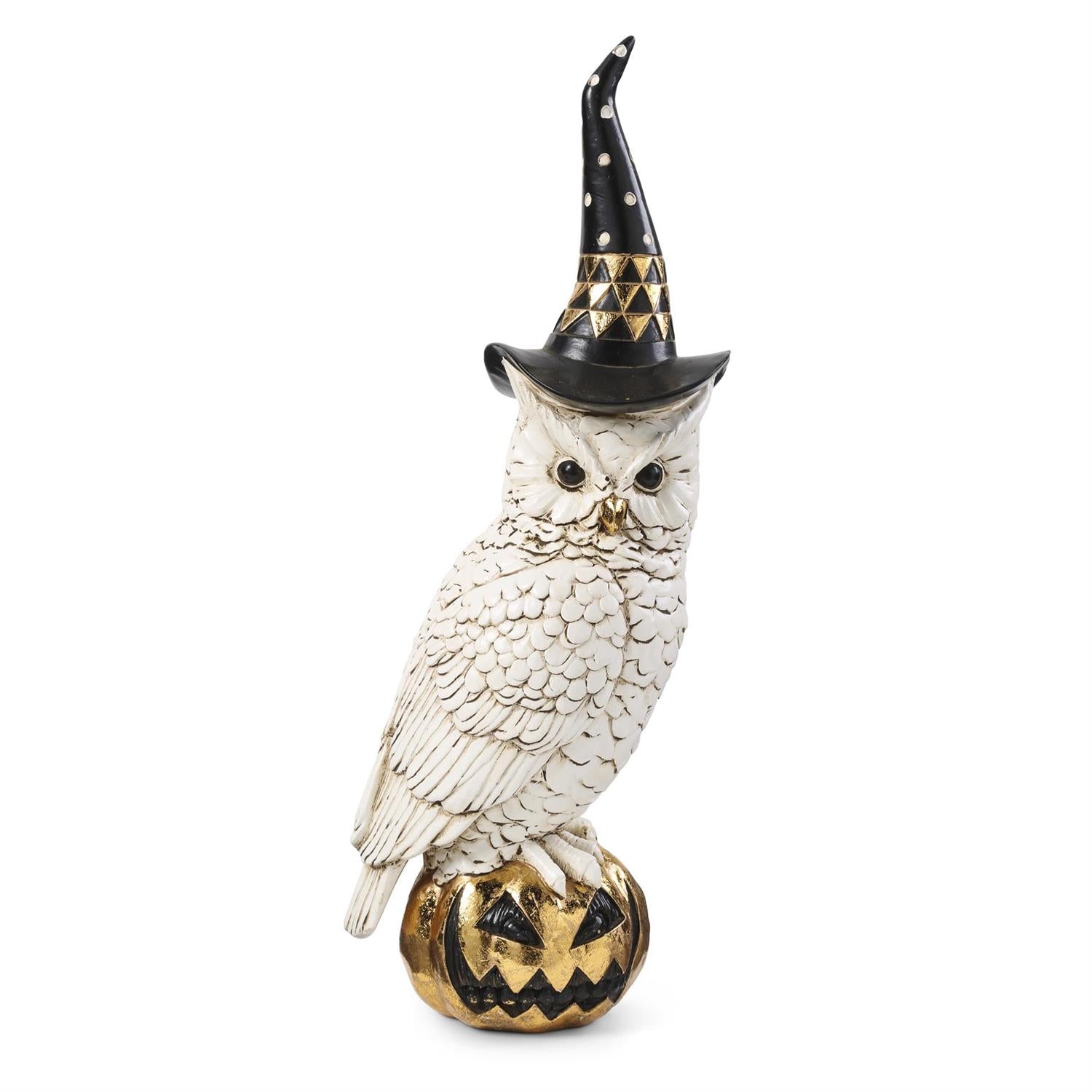 A white owl figurine wearing a black witch hat with gold accents and standing on a carved jack-o'-lantern pumpkin, photographed against a plain white background.