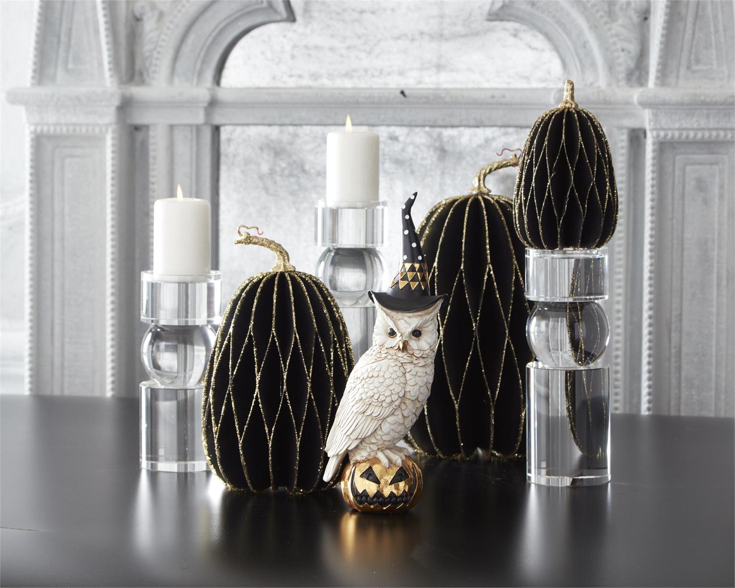Decorative pumpkins with owl and candles on a table in a room with large windows.